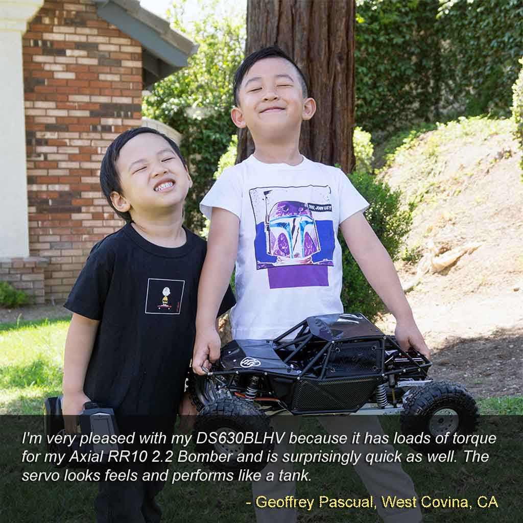 Two boys wearing big smiles and holding their toy truck because their parents were intent on introducing them to mechanical toys versus computer toys in hopes they'll grow up preferring to play outside instead of holing up in their room with a computer game from a belief good play habits begin from an early age.